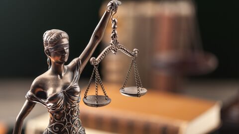 Justitia-Statue vor einem Bücherstapel