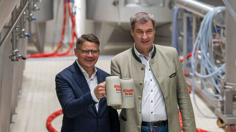 Die Ministerpräsidenten von Hessen und Bayern, Boris Rhein (links) und Markus Söder (rechts), bei Glaabsbräu, der ältesten Brauerei Südhessens, in Seligenstadt. Beide halten jeweils einen Bierkrug der Brauerei jeweils in ihrer rechten Hand.