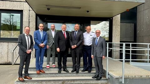 Von links nach rechts: Leiter der Polizeidirektion Frank Göbel, Polizeipräsident Torsten Krückemeier, Landtagsabgeordneter Sebastian Sack, Oberbürgermeister Thomas Spieß, Innenminister Roman Poseck, Leiter des Polizeireviers Oliver Bauer und Landespolizeipräsident Robert Schäfer. Sie stehen gemeinsam auf einer Treppe vor einem Gebäude.